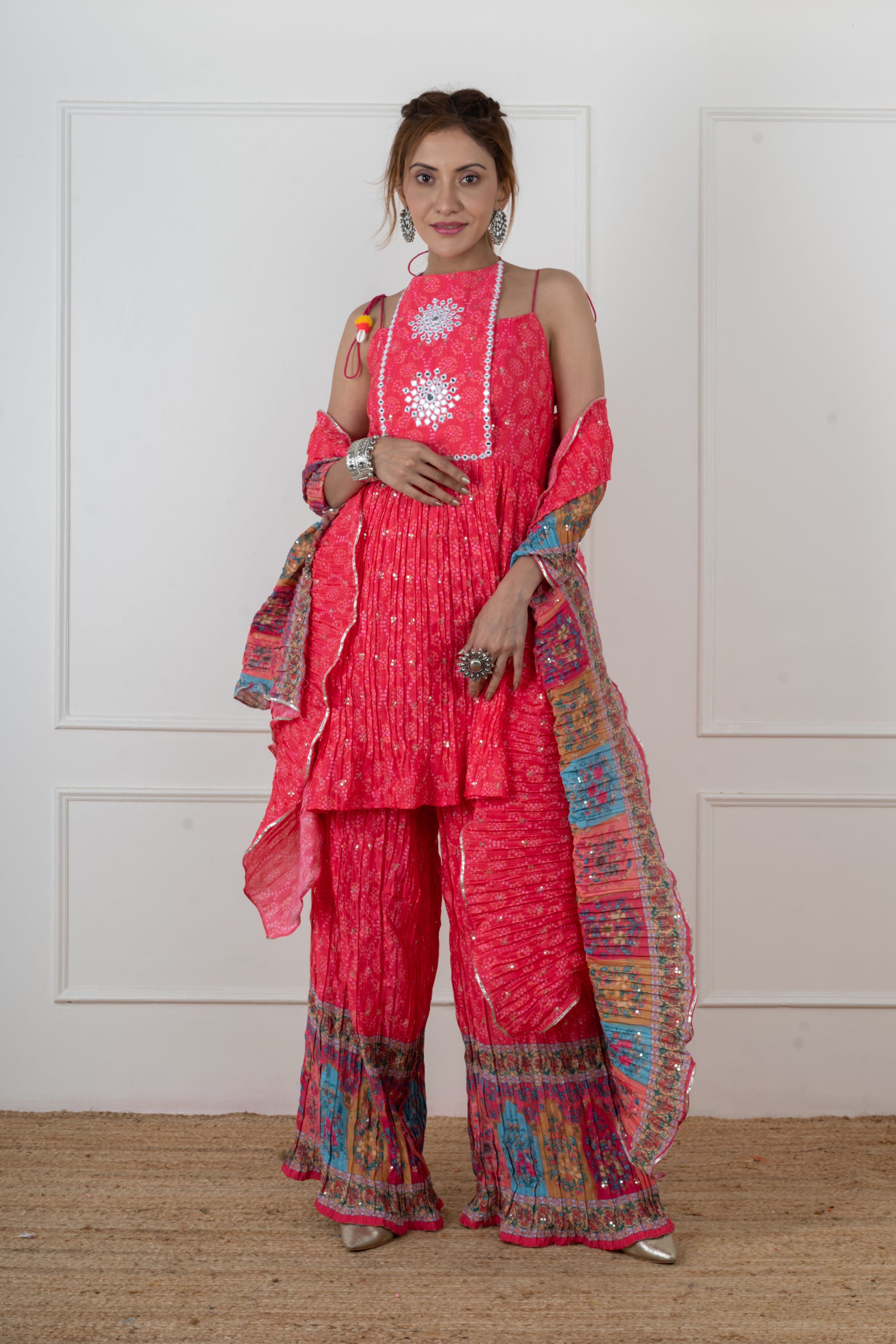 Woman wearing pink Bandhani mirror work kurta palazzo set, sleeveless halter neck